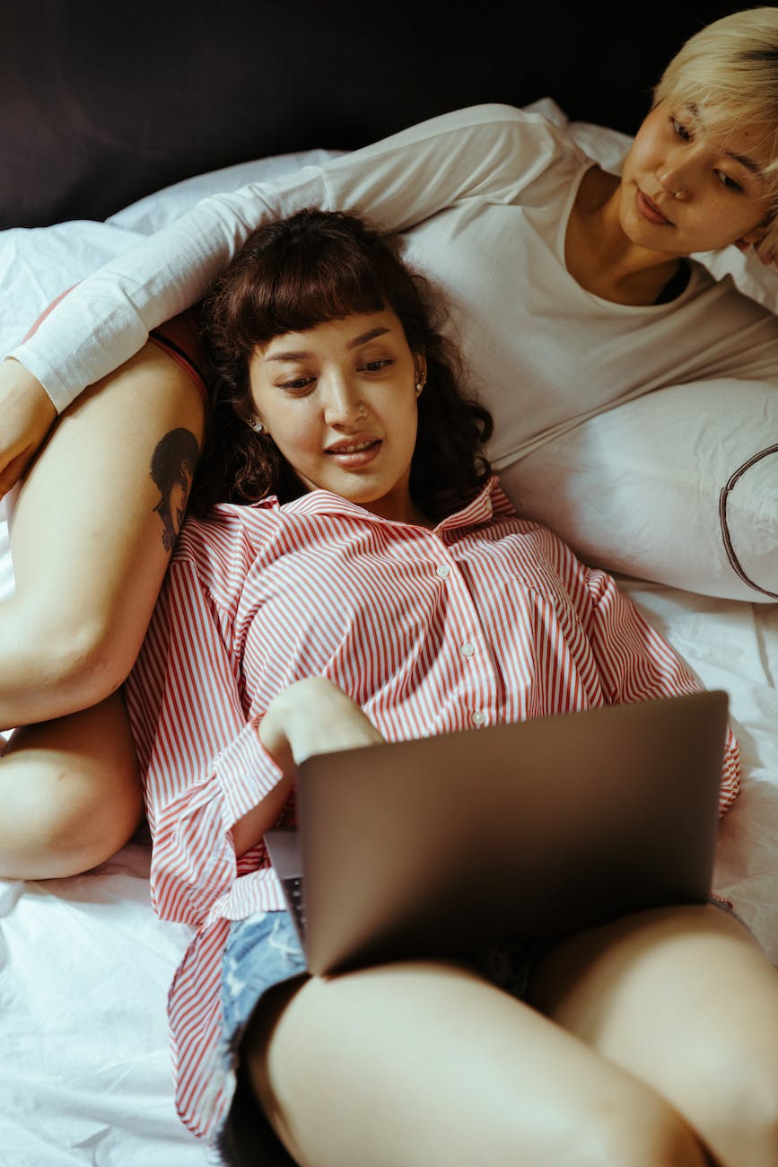 women in bed looking at a laptop