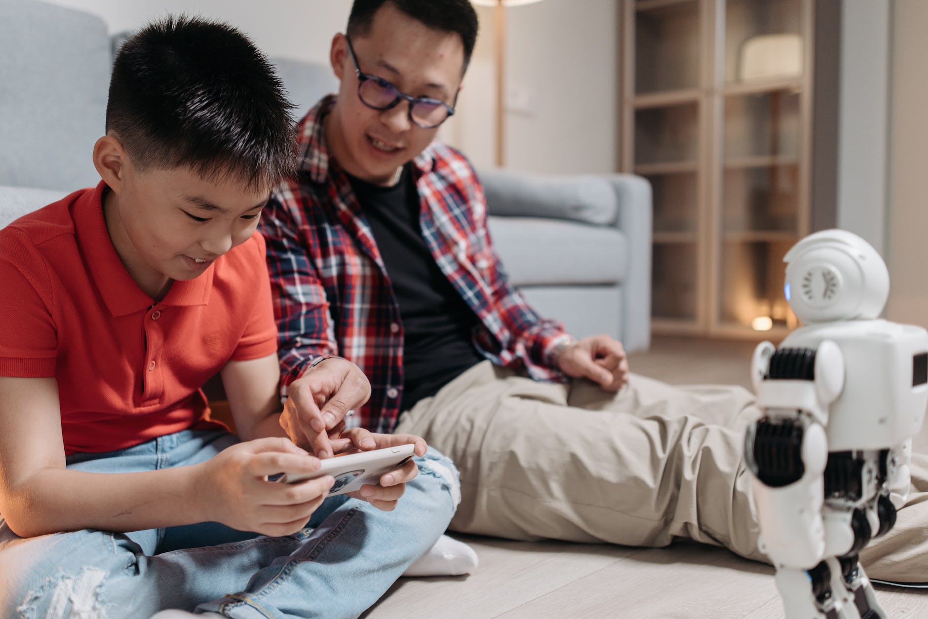 a man teaching his son how to control the robot using mobile phone