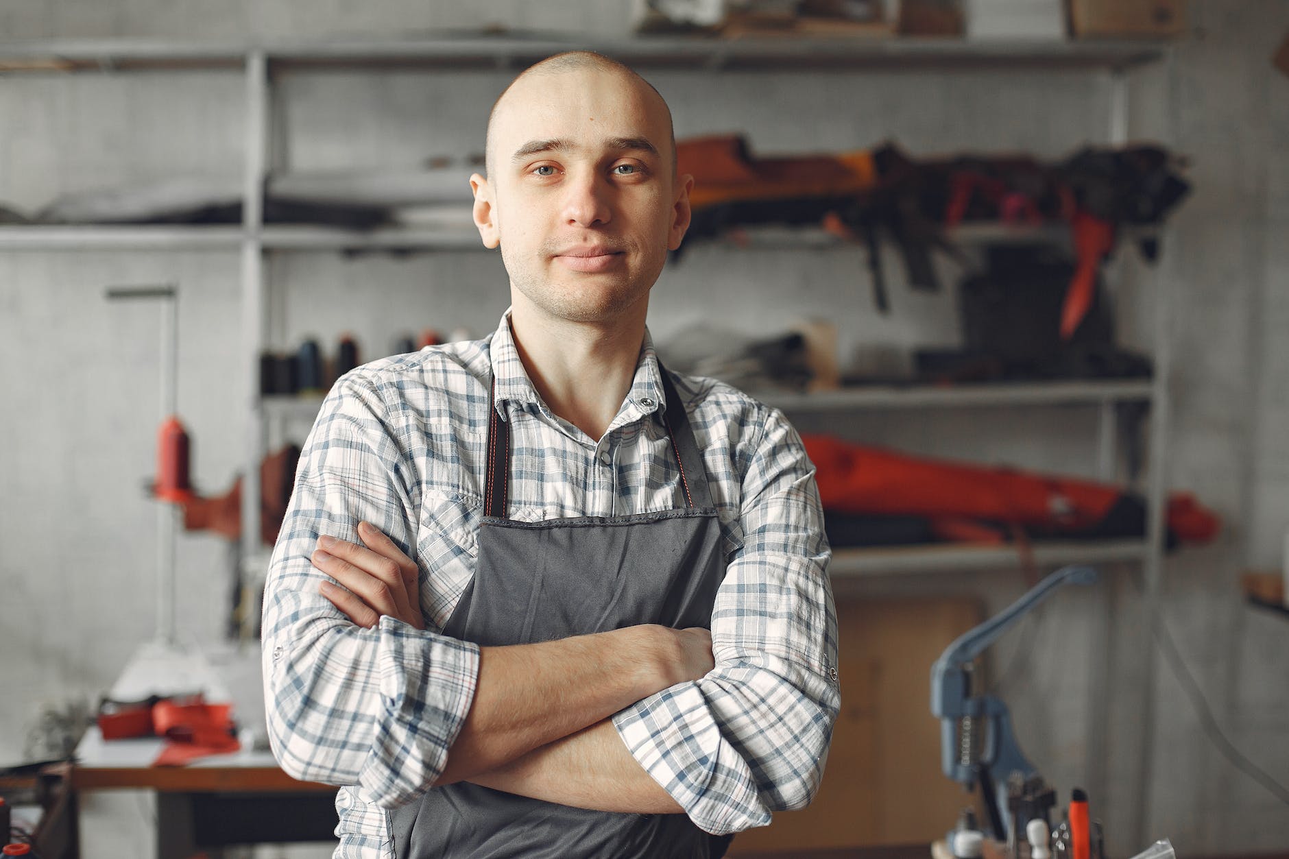 cheerful young tanner man in apron in workshop