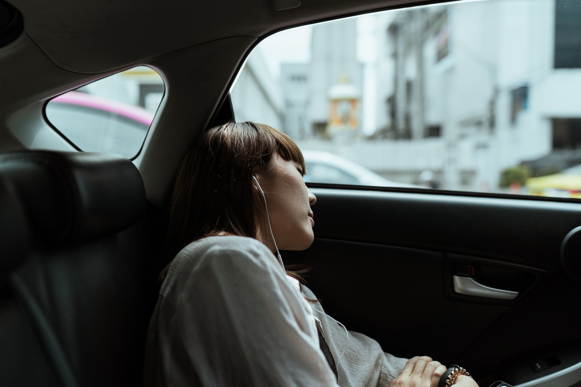 calm woman resting in car backseat with earphones