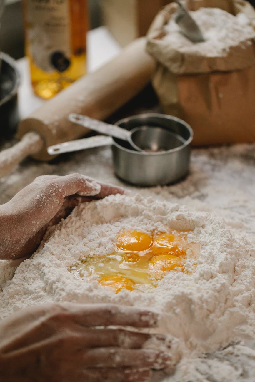 faceless woman making pasta dough with flour and eggs in kitchen